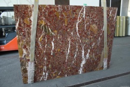 Płyta marmuru Red Marble, intensywnie czerwono-brązowe tło z żółtymi wstęgami i białymi, pionowymi żyłkami.