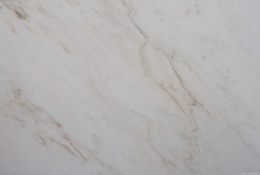 Zbliżenie marmuru Rhino White szczotka, miękkie beżowe smugi na mlecznobiałym tle o szczotkowanej strukturze.