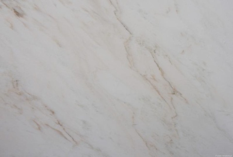 Zbliżenie marmuru Rhino White szczotka, miękkie beżowe smugi na mlecznobiałym tle o szczotkowanej strukturze.