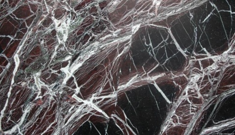 Marmur Rosso Levanto, ciemnoczerwone tło z intensywnymi białymi żyłkami i kontrastowymi czarnymi fragmentami.