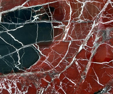 Zbliżenie marmuru Rosso Levanto, intensywna czerwień z białymi żyłkami i ciemnymi łupkowymi akcentami.