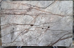 Płyta marmuru Silver River szlif, szare tło z nieregularnymi brązowymi żyłami tworzącymi dynamiczny, kamienny rysunek.