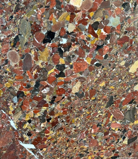 Zbliżenie płyty marmuru Teracco w odcieniach czerwieni, żółci i brązu z nieregularnymi kolorowymi fragmentami.