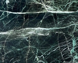 Zbliżenie struktury marmuru Verde Tinos, ciemnozielona płyta z jasnymi, nieregularnymi żyłkami