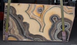 Slab onyksu Arco Irys o miodowo-kremowej kolorystyce z kontrastującymi grafitowymi pasmami.