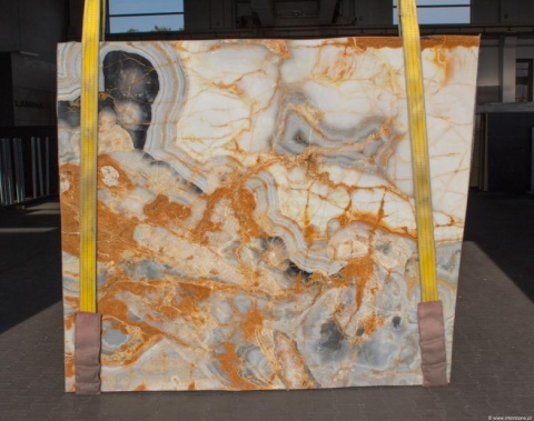 Onyks Avion Blue slab w jasnych kremowo-szarych tonach z bursztynowymi żyłkami i warstwową strukturą.