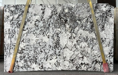 Płyta granitu Orion White, jasne tło z ciemnym, nieregularnym użyleniem, widok całej tafli w hali