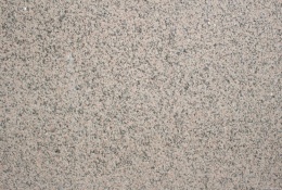 Zbliżenie struktury granitu Rosa Porrino płomień, drobnoziarnista różowo-szara powierzchnia z ciemnymi punktami