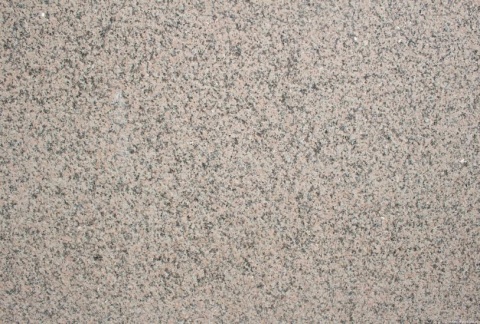 Zbliżenie struktury granitu Rosa Porrino płomień, drobnoziarnista różowo-szara powierzchnia z ciemnymi punktami