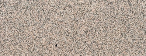 Zbliżenie granitu Rosa Porrino poler, drobnoziarnista różowo-szara powierzchnia z ciemniejszymi punktami