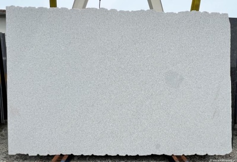 Płyta granitowa Silver Bianco, wykończenie młotek, widok całej płyty na stojaku na zewnątrz