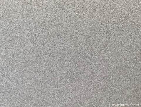 Zbliżenie granitu Silver Bianco płomieniowanego, jasnoszara drobnoziarnista powierzchnia o szorstkiej fakturze