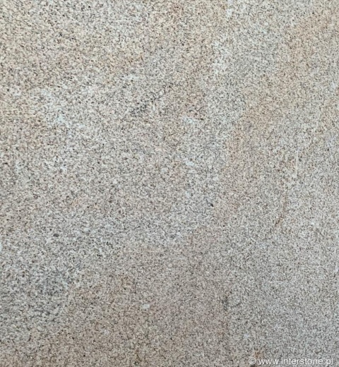 Zbliżenie struktury granitu Silvestre Gold młotek – beżowo-piaskowe, drobnoziarniste tło.