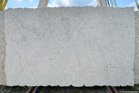 Jasna płyta granitu Silvestre Gold młotek ustawiona na zewnątrz – równomierne, piaskowe użylenie.