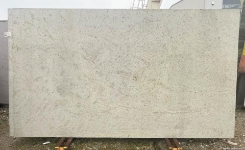 Płyta granitu Spring White ustawiona pionowo na zewnątrz – jasny kamień o subtelnym, nakrapianym wzorze.