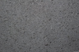 Zbliżenie granitu Steel Grey płomień – szary, drobnoziarnisty wzór i chropowata faktura płomieniowana.