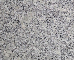 Zbliżenie granitu Strzegom poler – jasna, drobnoziarnista struktura z czarnymi i szarymi punktami.