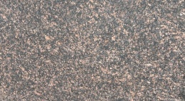 Zbliżenie granitu Tan Brown płomień – drobnoziarnista struktura z brązowymi wtrąceniami, faktura płomieniowana.