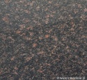 Detal granitu Tan Brown poler – ciemne tło z ciepłymi, brązowymi kryształami; powierzchnia polerowana
