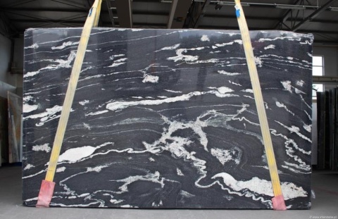 Płyta granitu Titanium Black – duży slab w ciemnym kolorze z białym, falującym użyleniem; pasy transportowe.