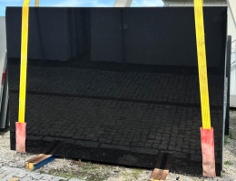 Granit Ultimate Black – czarna płyta w dużym formacie na placu, pasy transportowe i odbicia na powierzchni.