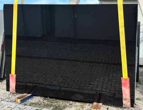 Granit Ultimate Black – czarna płyta w dużym formacie na placu, pasy transportowe i odbicia na powierzchni.