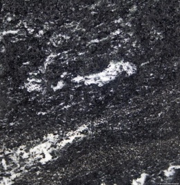 Zbliżenie granitu Via Lattea – ciemna, ziarnista struktura z białymi przeżyleniami i jasnymi wtrąceniami.