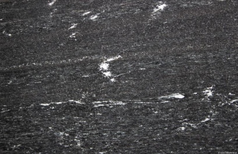 Detal granitu Via Lattea – czarne tło z cienkimi, białymi żyłami i lekkim kierunkowym rysunkiem kamienia.