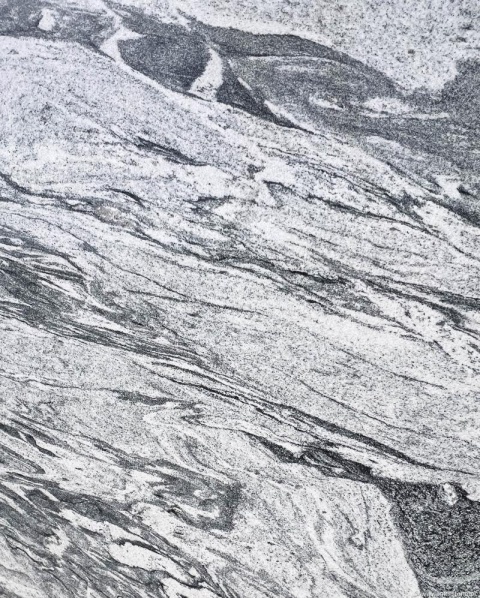 Detal granitu Viscount White poler – falujące pasma grafitu i szarości, naturalny rysunek kamienia.