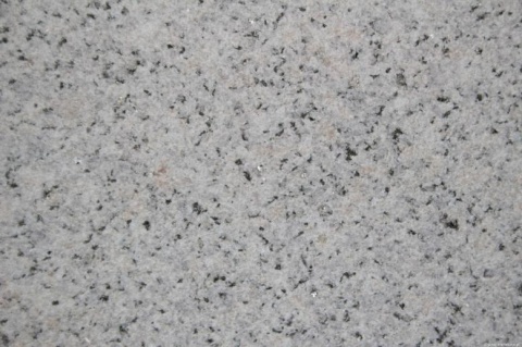 Zbliżenie granitu White Silver – drobnoziarnista struktura jasnej szarości z ciemnymi punktami i kryształkami.