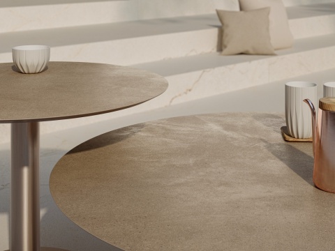 Okrągłe stoły ze spieku kwarcowego Marazzi Concrete Look Slow Argilla w ciepłej, naturalnej kolorystyce.