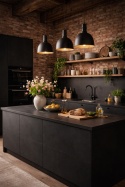 Industrialna kuchnia z blatem z czarnego spieku Nero Assoluto, ceglana ściana i wiosenne dodatki w jasnych kolorach.
