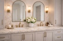 Blat łazienkowy ze spieku Fusion White z podwójną umywalką, złotą armaturą i jasną elegancką zabudową.