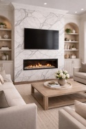 Ściana TV z kominkiem w salonie wykończona spiekiem Invisible White, jasne meble i elegancka zabudowa.