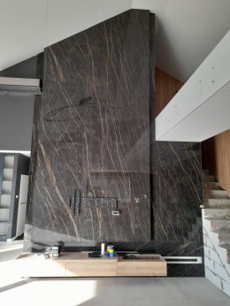 Ściana TV ze spieku Noir Desir z pionowym użyleniem, nowoczesne wnętrze z antresolą i drewnianymi elementami.