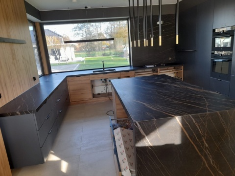 Wyspa kuchenna ze spieku Noir Desir z widocznym użyleniem, elegancka kuchnia z drewnem i czarnymi dodatkami.