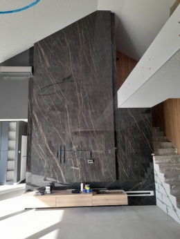 Ściana TV ze spieku Noir Desir z pionowym użyleniem, nowoczesne wnętrze z antresolą i drewnianymi elementami.