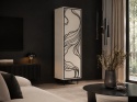 Witryna Patina 60 w kolorze kaszmir z czarnym ornamentem i stelażem, ustawiona w nowoczesnym salonie z czarną ścianą.