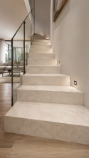 Jasne schody wewnętrzne wykończone Grespania Porfido Sand Natural 20 mm ze szklaną balustradą