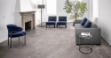 Posadzka Marazzi Ardesia Cenere 120 × 120 cm w eleganckim salonie z kominkiem, granatowymi fotelami i szarą sofą