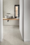 Płytki Marazzi Cementum Ash na podłodze i ścianach jasnej łazienki z drewnianym blatem i nablatową umywalką