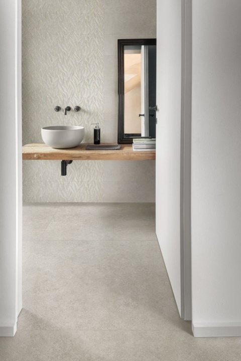 Płytki Marazzi Cementum Ash na podłodze i ścianach jasnej łazienki z drewnianym blatem i nablatową umywalką