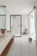 Marazzi Onice Avorio Lux na ścianach i podłodze jasnej łazienki z czarnymi detalami, drewnem i dużymi przeszkleniami