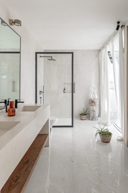 Marazzi Onice Avorio Lux na ścianach i podłodze jasnej łazienki z czarnymi detalami, drewnem i dużymi przeszkleniami