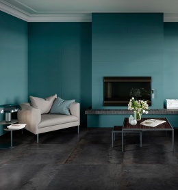 Salon z niebiesko-turkusową okładziną ścienną inspirowaną kolorem Azzurro, zestawioną z ciemną podłogą i jasnymi meblami