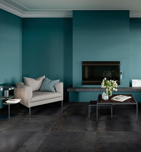 Salon z niebiesko-turkusową okładziną ścienną inspirowaną kolorem Azzurro, zestawioną z ciemną podłogą i jasnymi meblami