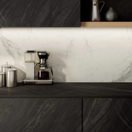 Nowoczesna kuchnia z ciemnymi powierzchniami Marazzi Bahia Black zestawionymi z jasną, marmurową okładziną ścienną