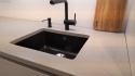 Blat TechniStone Noble Ivory White z czarnym zlewem i baterią w nowoczesnej kuchni.