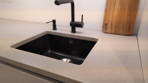 Blat TechniStone Noble Ivory White z czarnym zlewem i baterią w nowoczesnej kuchni.
