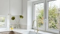 Blat TechniStone Noble Quartzite w jasnej kuchni z białą zabudową i złotymi detalami.
